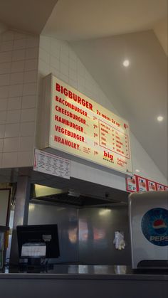 a large menu board above a counter in a restaurant or diners kitchen with white tiles on the walls