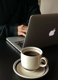 a cup of coffee and a laptop on a table