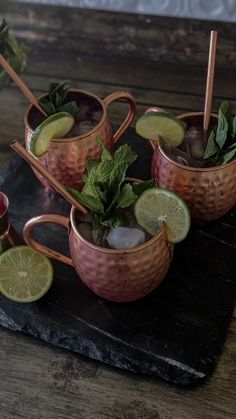 three copper mugs filled with drinks and garnishes