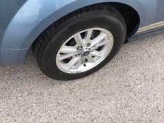 the front wheel of a blue car parked in a parking lot