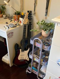 a guitar is sitting on top of a shelf next to a desk with plants and other items