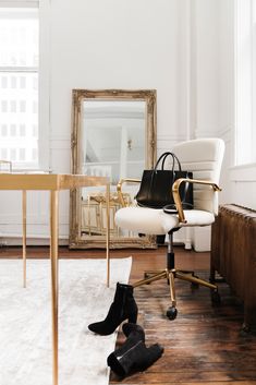 a white chair sitting in front of a desk with a black purse on top of it