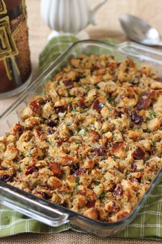 a casserole dish filled with stuffing and cranberries on a green cloth