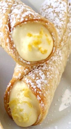 two pastries on a plate with powdered sugar and lemons in the middle