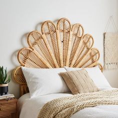 a bed with a large headboard made out of wicker and white linens