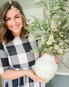 a woman holding a vase with flowers in it