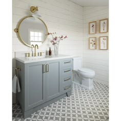 a bathroom with white and blue cabinets, a toilet and a mirror on the wall