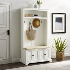 an entryway with a bench, potted plant and basket on the top shelf