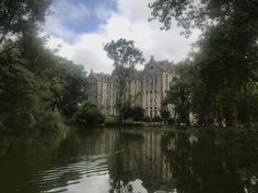 a large building sitting on top of a lush green field next to a body of water