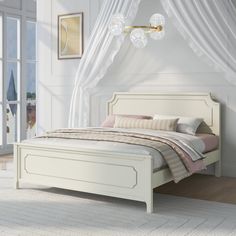 a white bed sitting in a bedroom under a chandelier next to a window