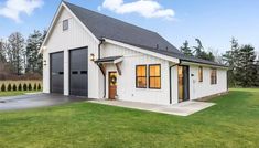 a white house with black shutters and two garage doors on the side of it