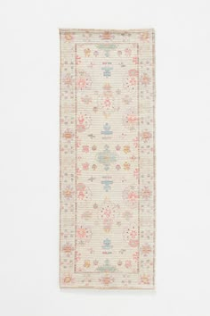 a white rug with flowers and leaves on the bottom is hanging up against a wall