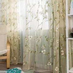 the curtains in this room are decorated with flowers and green leaves, while the chair is next to the window