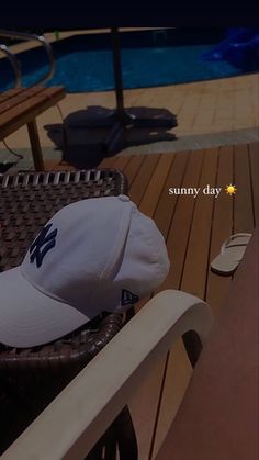 a white hat sitting on top of a chair next to a swimming pool with the caption sunny day