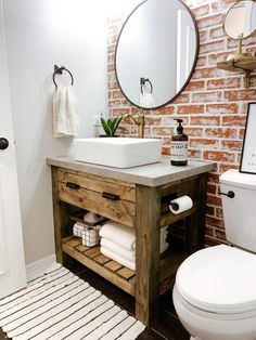 a white toilet sitting next to a wooden sink vanity in a bathroom under a round mirror