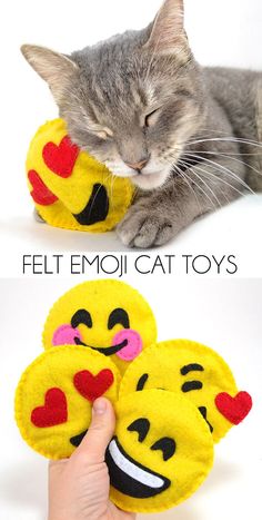 a cat laying down next to two emoji toy's with faces on them