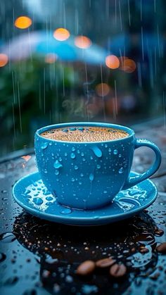 a cup of coffee sitting on top of a blue saucer covered in raindrops