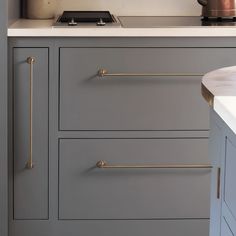 a kitchen with gray cabinets and white counter tops, gold pulls on the handles that are brass