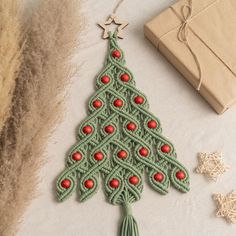 a crocheted christmas tree ornament next to a gift box and twine