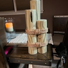 four wooden logs tied up with rope and sitting on a table next to a candle