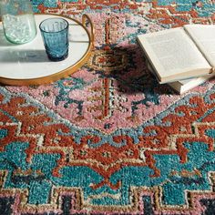 an open book is sitting on the floor next to a glass and a candle holder