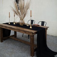 a wooden table topped with a black cloth covered tablecloth and gold candlesticks