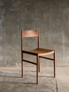 a wooden chair sitting in front of a concrete wall