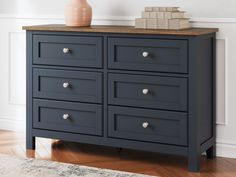 a black dresser with drawers and a vase on top