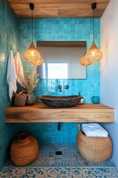 a bathroom with blue tiles and wooden fixtures on the counter, along with two hanging lights