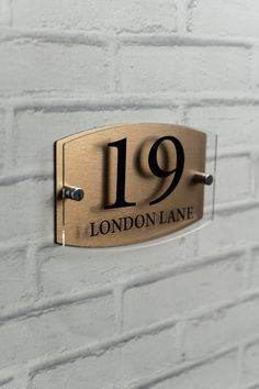 a metal plaque with the number 19 hanging on a white brick wall in london lane