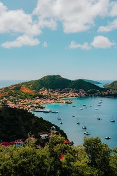 boats are floating in the water near some hills and trees on a sunny day with blue sky