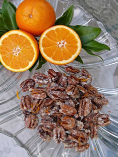 two oranges and some nuts on a glass plate