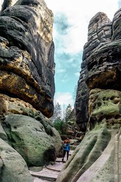 two people are walking between some large rocks