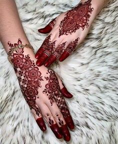 two hands with henna tattoos on them, one is red and the other is white