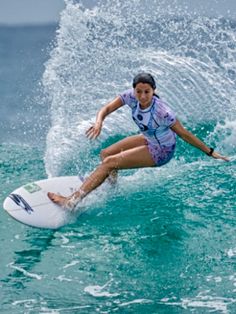 a woman riding a wave on top of a surfboard