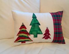 two christmas trees on a white pillow sitting on a couch