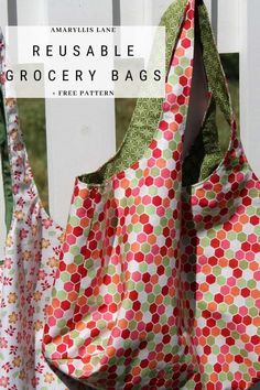 two reusable grocery bags sitting next to each other on a white picket fence