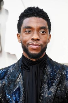 a close up of a person wearing a black shirt and blue jacket with an animal print on it