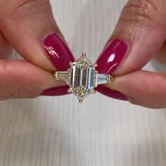 a woman's hand holding a pink manicured nail with a diamond ring on it