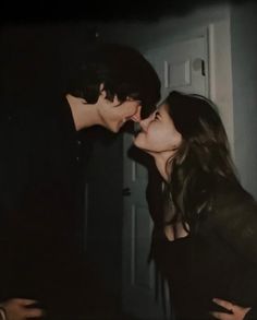 two people kissing each other in front of a door