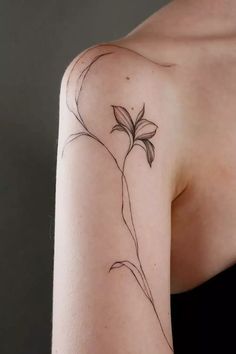 a woman's arm with a flower tattoo on the left side of her shoulder