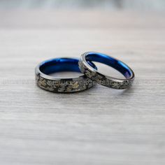 two wedding rings sitting on top of a wooden table with blue glass in the middle