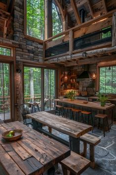 a wooden table sitting inside of a kitchen next to a stone wall and ceiling covered in windows