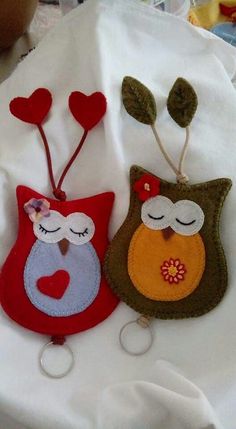 two handmade owl keychains sitting on top of a white cloth covered table