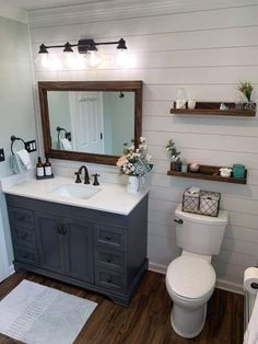 a white toilet sitting next to a sink in a bathroom under a mirror and lights