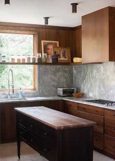 a kitchen with wooden cabinets and marble counter tops, along with an island in the middle