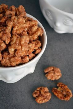 a white bowl filled with walnuts next to two smaller bowls