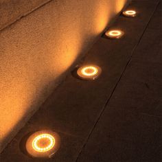 some lights that are on the side of a wall and in the ground next to each other