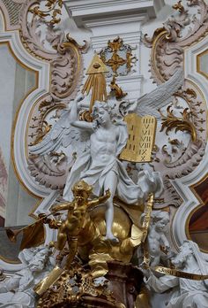 an ornately decorated clock with gold and white decorations on the front wall, along with angel figurines