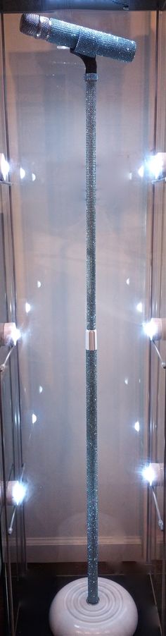 a large metal object on display in a glass case with lights around it and some wires attached to the pole